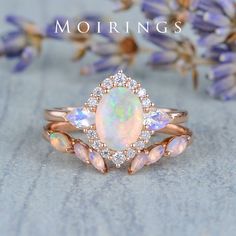 an opal and diamond ring with the words mohriings on it in front of some flowers