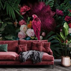 a red couch sitting in front of a wall with flowers and birds on top of it