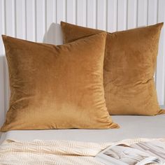 two brown pillows sitting on top of a bed next to a white headboard and wall