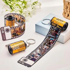 a camera and some pictures are on a table next to a box with a keychain