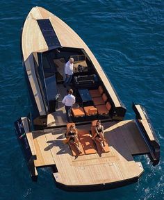 two people are sitting on the back of a boat in the water while another person stands near them