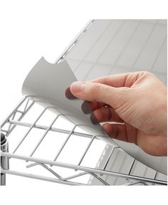 a hand is holding onto the side of a shelf with metal bars attached to it