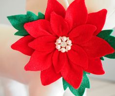 a red poinsettia with green leaves and pearls on it's center