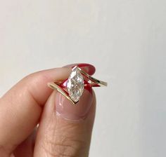 a woman's hand holding an engagement ring with a diamond on the top and side