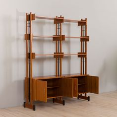 a wooden bookcase with two drawers and one door on the side, in front of a white wall