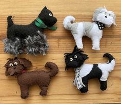 four different types of stuffed dogs on a wooden surface with one black dog, one white dog and one brown dog