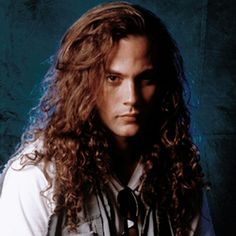 a man with long curly hair wearing a tie