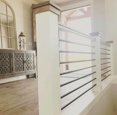 the inside of a house with wood floors and white railings in front of a window