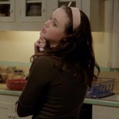 a woman standing in a kitchen talking on a cell phone