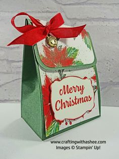 a small christmas bag with a red bow on it's handle and the words merry christmas