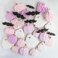 decorated cookies are arranged in the shape of bats, pumpkins and ghostes on a white surface