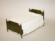 a miniature bed with white sheets and brown headboard