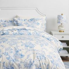 a blue and white bed in a bedroom next to a night stand with two lamps