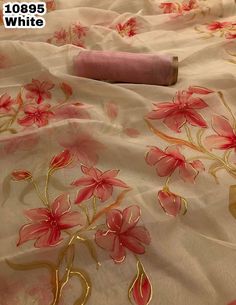 a bed covered in pink and gold flowers on it's side with a white comforter