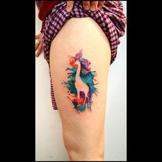 a woman's thigh with a colorful bird tattoo on it