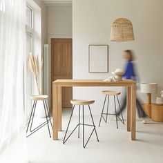 a table with two stools in front of it and a person walking past the table