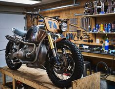 a motorcycle is sitting on top of a wooden platform in a shop with tools and other items