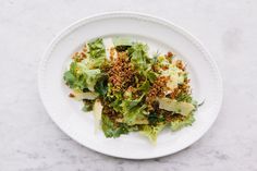 a white plate topped with lettuce covered in crumbs and seasoning