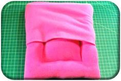 a pink blanket sitting on top of a green cutting board