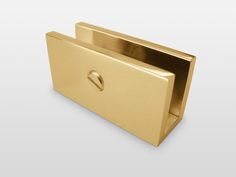 a gold metal object with a hole in the middle on a white background, it appears to be part of a business card holder