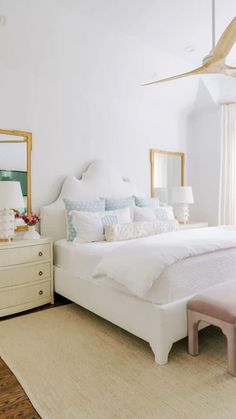 a bedroom with white furniture and large mirror on the wall above the bed, along with an area rug