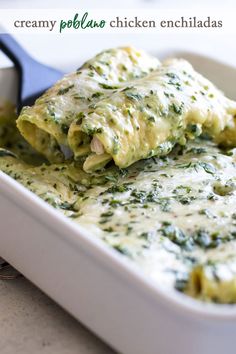 a white casserole dish filled with spinach and chicken enchiladas