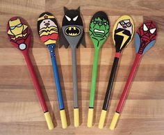 five different colored plastic spoons with cartoon characters on them sitting on a wooden surface