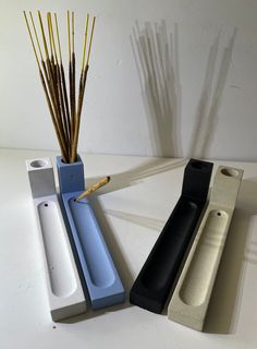 three different colored vases with sticks sticking out of them on a white counter top