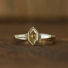 an engagement ring with two baguettes and three side stones on top of a wooden table