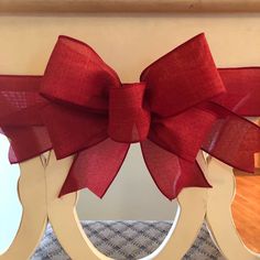 a large red bow on the back of a wooden chair with two mirrors behind it