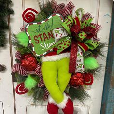 a christmas wreath with green and red decorations on the front door, hanging from a wooden door