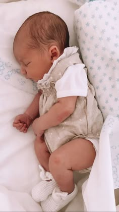 a baby is sleeping in a bed with white sheets and blue stars on the covers