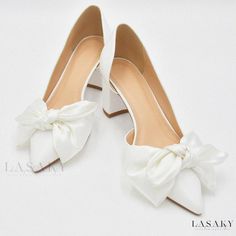 a pair of white high heel shoes with a bow