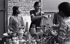 three women standing around a table with vases and pottery on it's sides