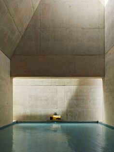 an indoor swimming pool in a building with concrete walls and flooring on the sides