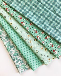 four different colored fabrics are stacked on top of each other, one is green and the other is blue