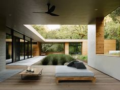 an outdoor living area with couches, tables and plants on the side of the house