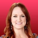 a woman with red hair and earrings smiling at the camera, against a pink background