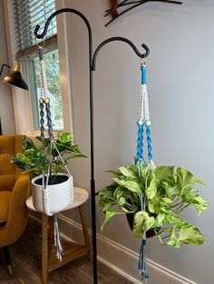 two potted plants are hanging from black metal poles in the corner of a room