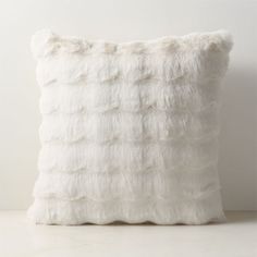 a white pillow with fluffy fur on the front and back of it, sitting on a table