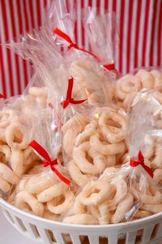 several bags of pretzels in a white bowl on a red and white striped tablecloth