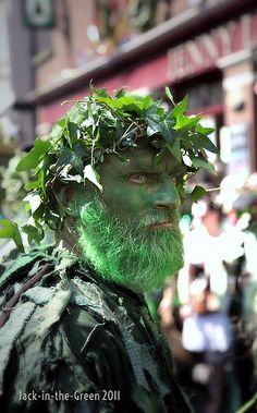 a man with green paint on his face and beard is standing in front of a crowd