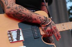 a person with tattoos on their arm playing an electric guitar at a music festival or concert