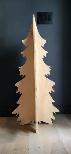 a wooden christmas tree sitting on top of a hard wood floor next to a wall