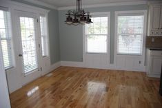 an empty living room with hard wood floors and white shuttered windows in the corner