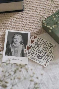 two pieces of paper that have been placed on a bed with flowers and books in the background