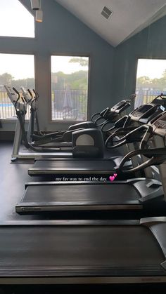 a row of treadmills in a gym with windows looking out onto the pool