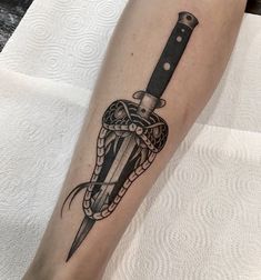 a black and white tattoo on the leg of a person with a knife in it