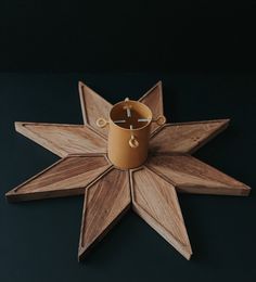 a wooden star decoration with a coffee cup on the center and candle holder in the middle