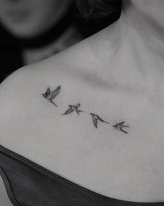 a woman's chest with three birds flying in the air on her left shoulder